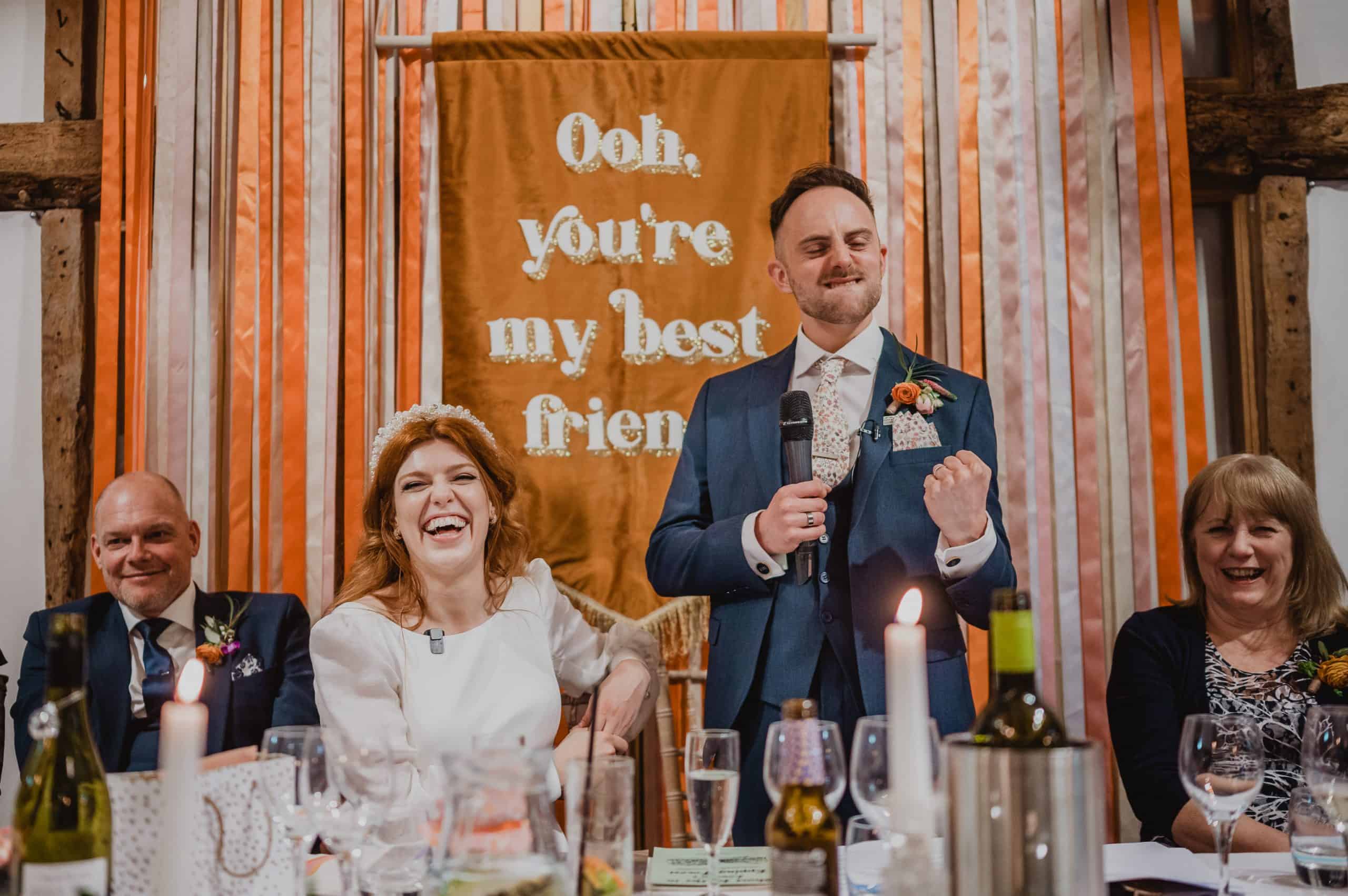 A groom celebrates making his bride laugh during the speeches