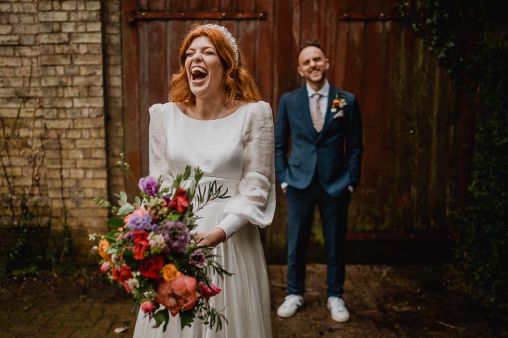 A bride laughs as her groom grins from behind her